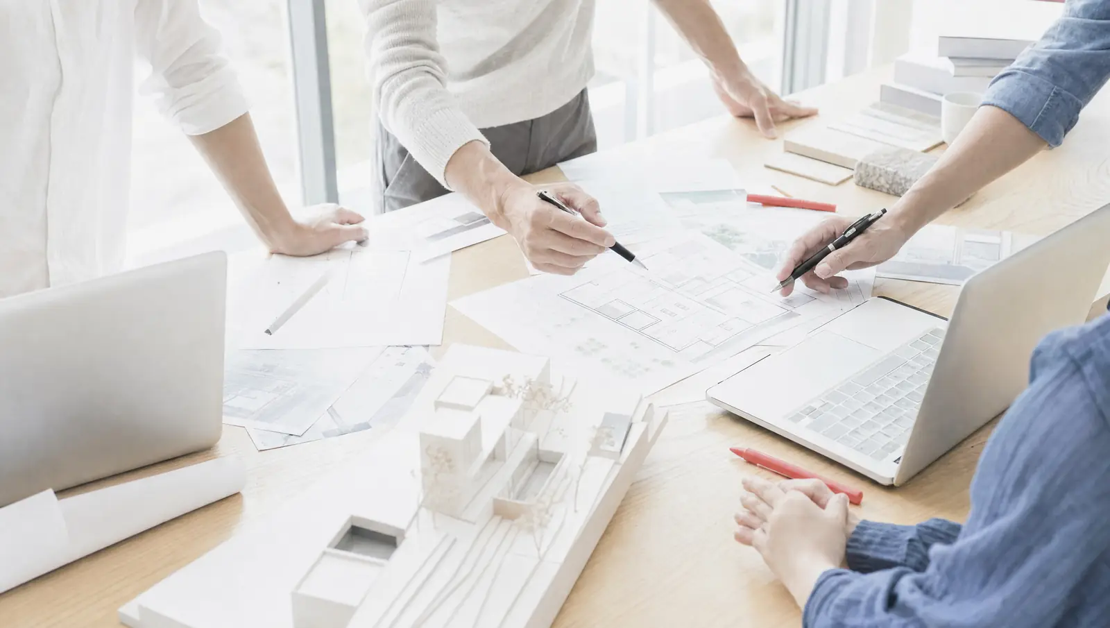 A team working around a table with laptops and architecture diagrams